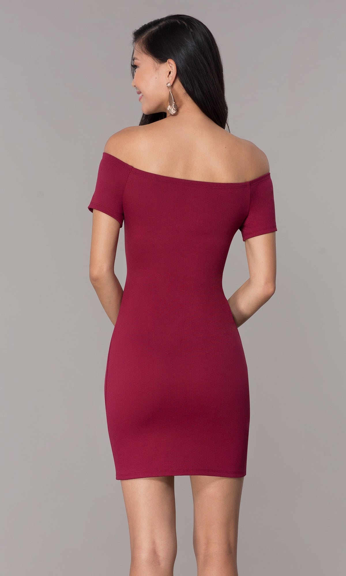 A woman faces away, wearing the Off-the-Shoulder Short Cut-Out Party Dress 3076—a fitted burgundy cocktail dress with short sleeves, set against a plain background.